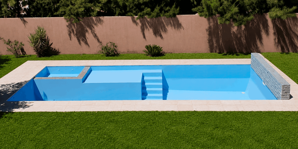 Piscina de material con jacuzzi y cascada construida en Rosario por RA Construcciones.