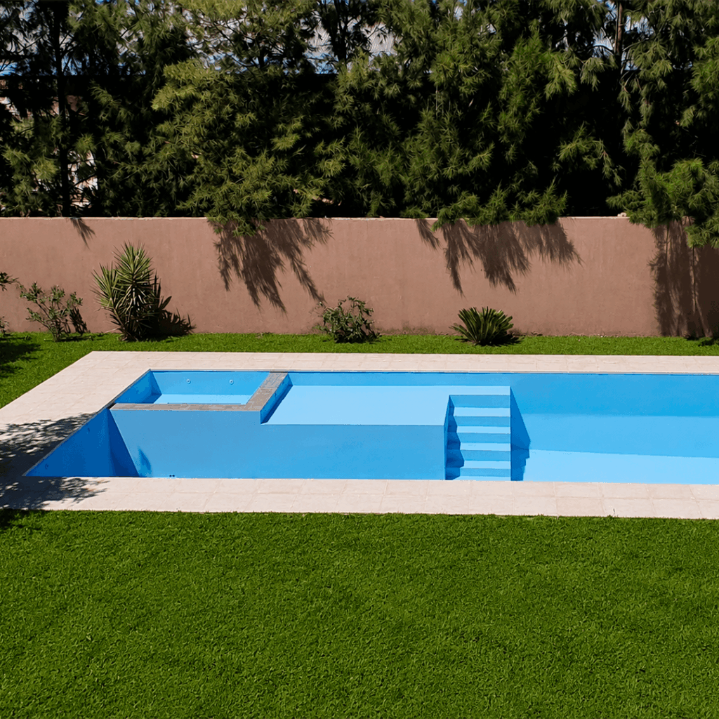 Piscina de material con jacuzzi y cascada construida en Rosario por RA Construcciones.